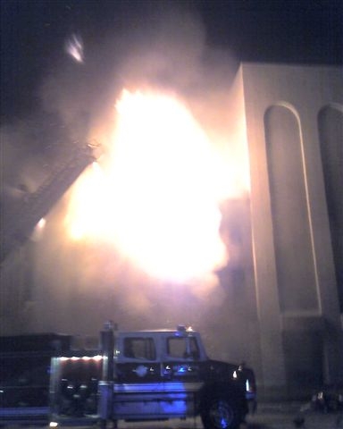 Fire truck fighting a roaring building fire.